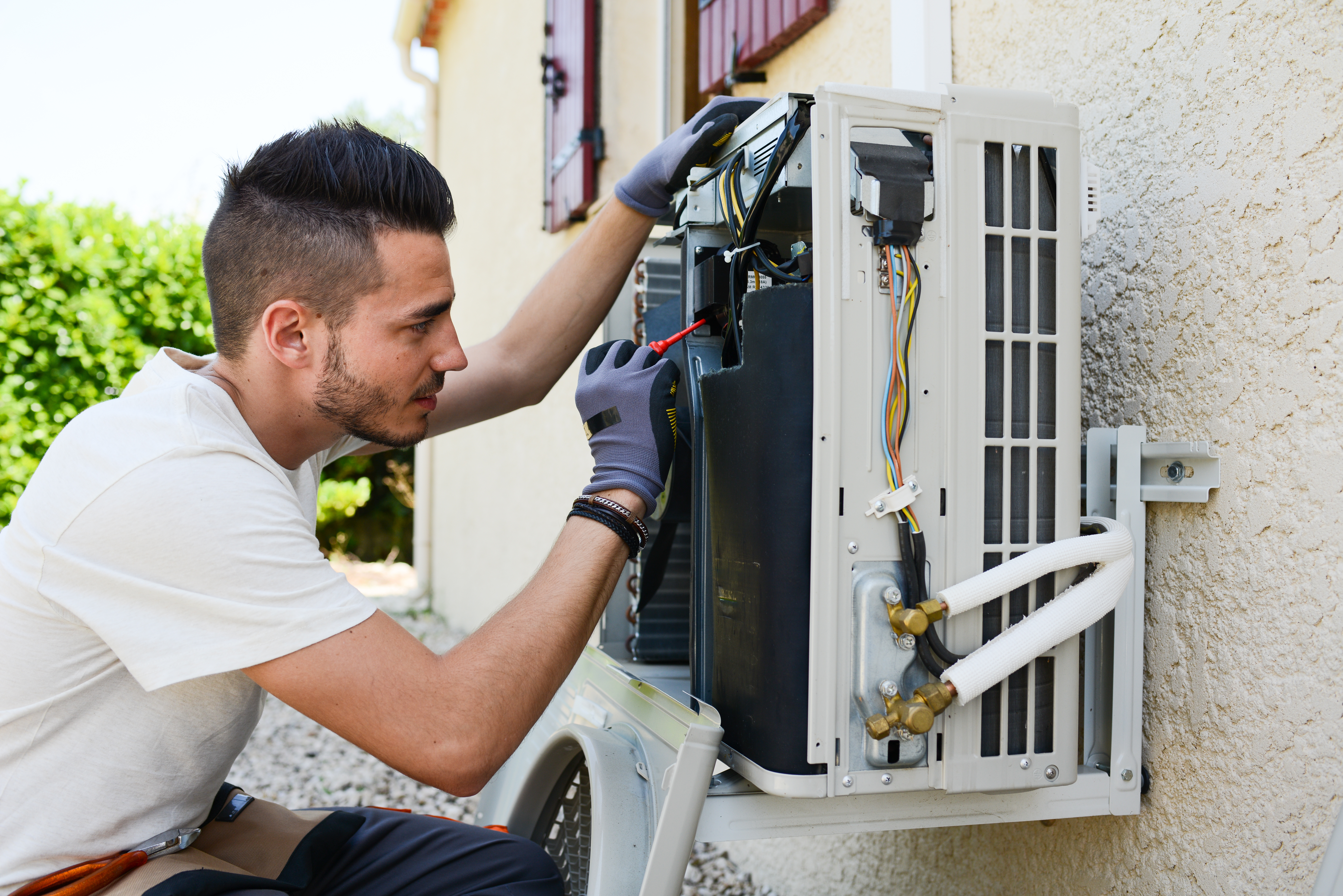 handsome young man electrician installing air conditioning in client house ac service